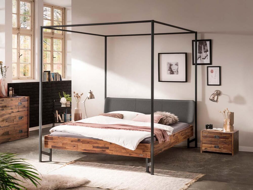 Modernes Schlafzimmer mit einem Himmelbett aus Holz und Metall, einem grau gepolsterten Kopfteil, weißer Bettwäsche, einem Nachttisch und einer Kommode aus Holz, Wandkunst, großen Fenstern und neutraler Einrichtung mit natürlichem Licht.
