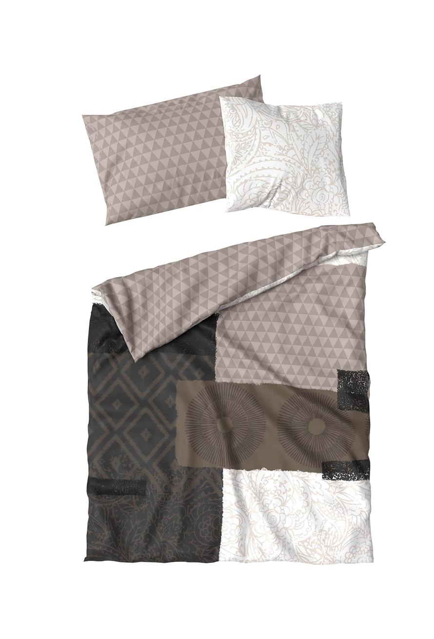 Ein ordentlich gemachtes Bett mit einer Bettdecke und zwei Kissen zeigt Bettwäsche Yeshia Lotus Création mit geometrischen, Paisley- und Kreismustern in Beige, Braun, Schwarz und Weiß für einen eklektischen modernen Look.
