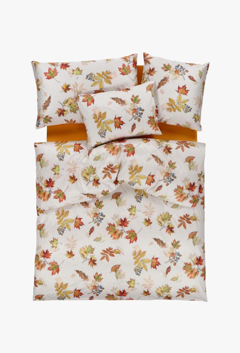 Ein hübsch gemachtes Bett mit der Bettwäsche Tamara-R Selection Windy: weiße Bettwäsche mit buntem Herbstblatt- und Eichelmuster, ergänzt durch passende Kissen. Die unifarbene, senfgelbe Bettwäsche bildet einen warmen Kontrast dazu.