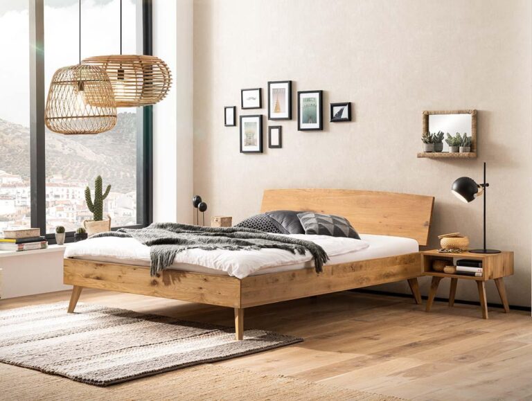 Ein modernes Schlafzimmer mit einem Holzbett, Nachttisch und neutraler Einrichtung. Große Fenster lassen viel natürliches Licht herein. Der Raum verfügt über Wandkunst, eine Stehlampe, Topfpflanzen und eine geflochtene Pendelleuchte über einem strukturierten Teppich.