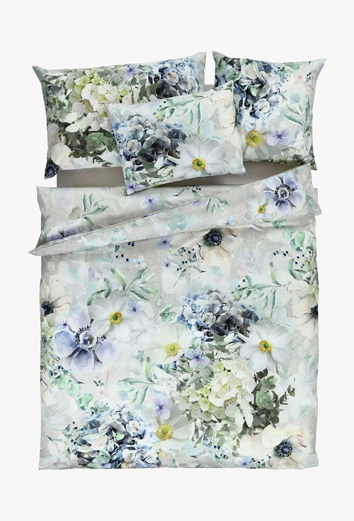 Ein Bettwäscheset mit Blumenmuster in sanften Weiß-, Blau- und Grüntönen, mit großen blühenden Blumen und Blattakzenten auf hellem Hintergrund. Enthält einen Bettbezug und vier passende Kopfkissen.