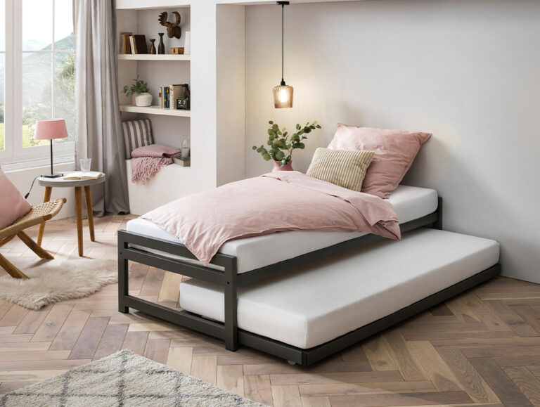 Ein modernes Schlafzimmer mit einem Rollbett aus schwarzem Metall. Das obere Bett ist mit rosafarbener Bettwäsche und Kissen ausgestattet, während das untere Bett ordentlich darunter verstaut ist. Regale, ein Stuhl und ein Fenster mit Blick auf die Landschaft vervollständigen den gemütlichen Raum.