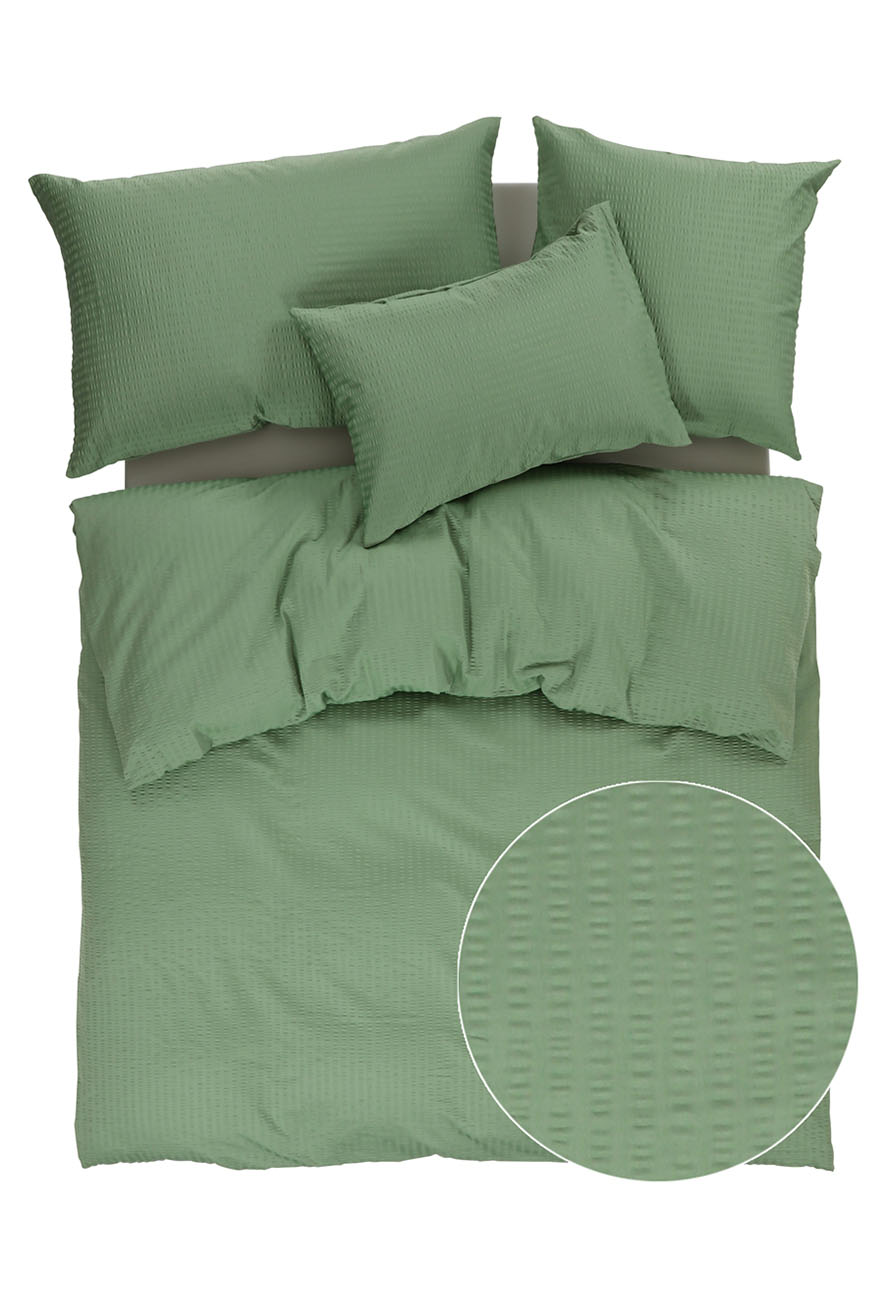 Ein Bett mit grünen Laken und Kissen.
