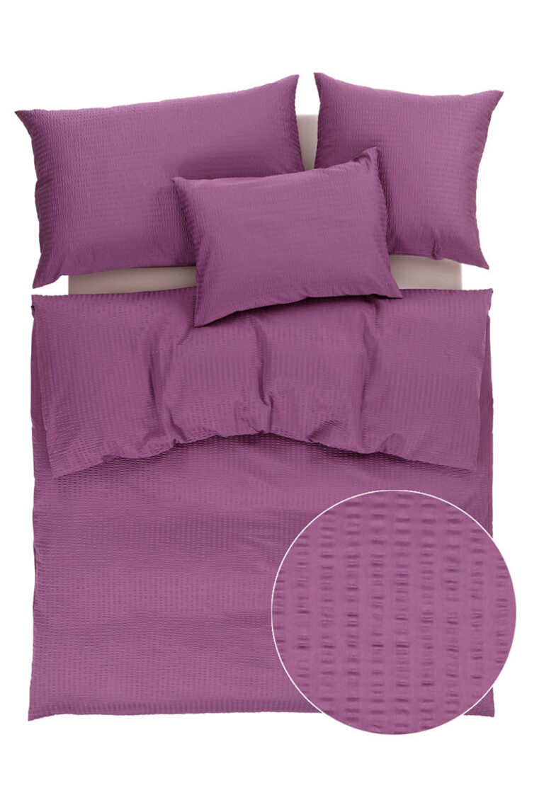 Ein lila Bett mit Kissen.