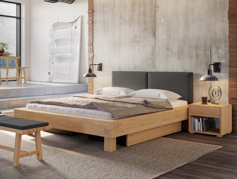 Ein modernes Schlafzimmer mit einem Bettgestell aus Holz, einem grauen Kopfteil, zwei Nachttischen, Hängeleuchten und abstrakten Wandbildern. Der Raum verfügt über Beton- und Ziegelwände sowie große Fenster, durch die Tageslicht hereinströmt.