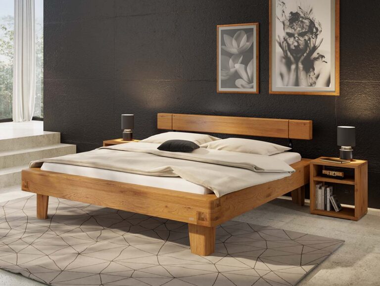 Ein modernes Schlafzimmer mit einem Bettgestell aus Holz, weißer Bettwäsche, zwei Nachttischen mit Lampen, einem geometrischen Teppich und zwei gerahmten Kunstwerken an einer dunklen Akzentwand. Sonnenlicht strömt durch ein Fenster auf der linken Seite herein.