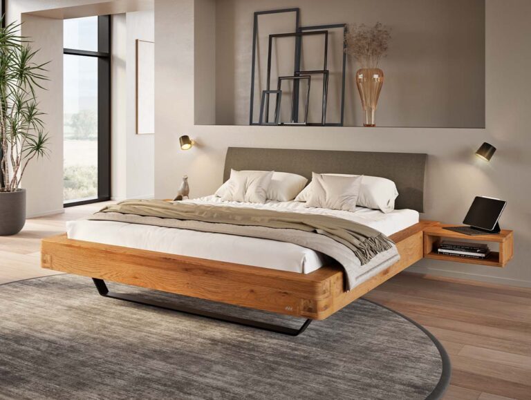Ein modernes Schlafzimmer mit einem schwebenden Holzbett, einem grauen gepolsterten Kopfteil, neutraler Bettwäsche, Wanddekoration und Nachttischen. Große Fenster und Zimmerpflanzen runden das minimalistische, gemütliche Design ab.