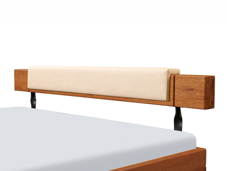 Ein Bettgestell aus Holz mit einem hellbeigen, gepolsterten Kopfteil und schwarzen Metallstützen, aufgenommen aus einer schrägen Seitenansicht.