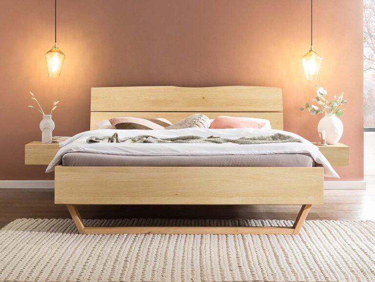 Ein modernes Holzbett mit einem beigen Teppich, einer braunen Akzentwand, zwei hängenden Pendelleuchten, schwebenden Nachttischen und dekorativen Vasen mit Blumen auf beiden Seiten. Die Bettwäsche ist weiß, dazu kommen neutrale Kissen und eine grüne Tagesdecke.
