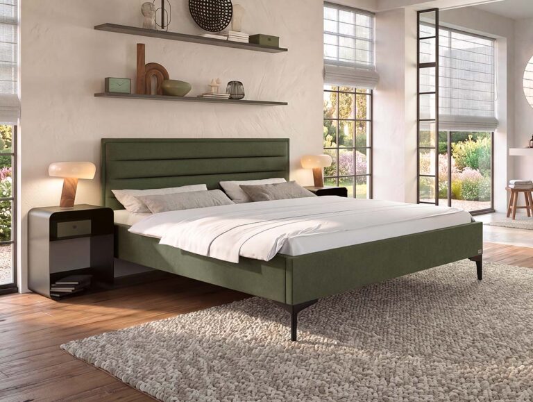 Ein modernes Schlafzimmer mit einem grün gepolsterten Bett, zwei Nachttischen mit Lampen, einem strukturierten Teppich, großen Fenstern und Regalen mit Dekoartikeln an der Wand. Das einfallende Sonnenlicht schafft eine helle, gemütliche Atmosphäre.