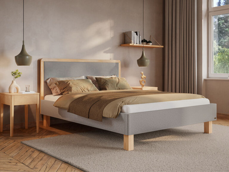 Ein modernes Schlafzimmer mit einem hellgrauen Bett, brauner Bettwäsche, Holzmöbeln, Hängelampen, einem Fenster mit beigen Vorhängen und einfallendem Sonnenlicht. An der Wand über dem Bett befinden sich Regale mit Büchern und Dekoartikeln.