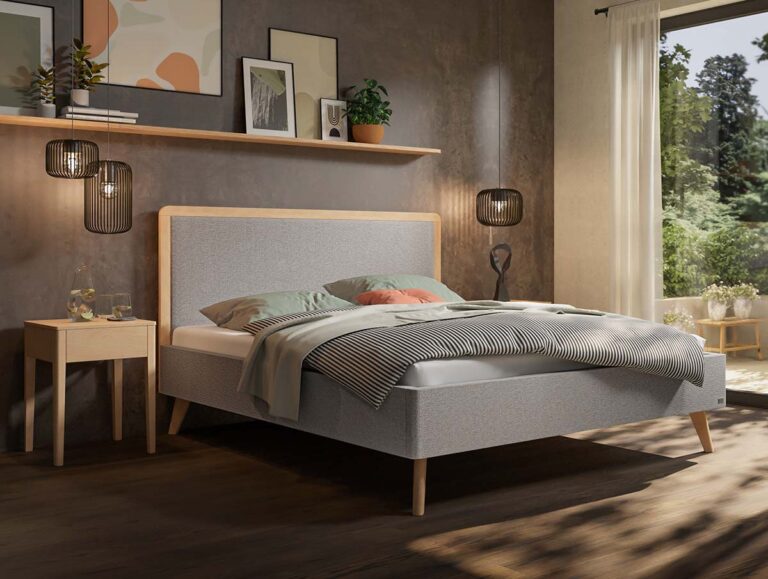 Ein modernes Schlafzimmer mit einem grauen Polsterbett, pastellfarbenen Kissen, einem Nachttisch aus Holz, Hängeleuchten, einem Regal mit Pflanzen und Kunstwerken sowie Sonnenlicht, das durch ein Fenster mit Blick ins Grüne hereinströmt.
