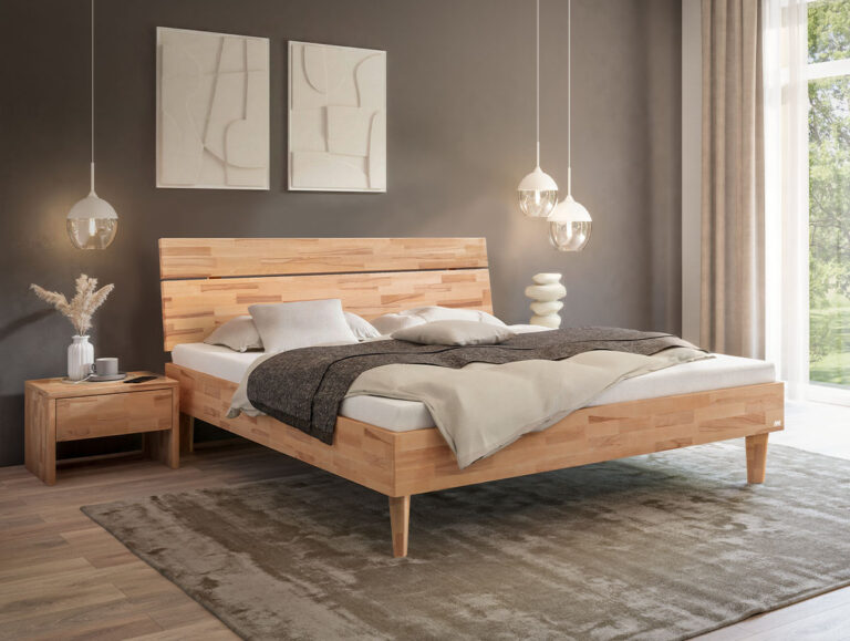 Ein Bettgestell aus hellem Holz mit einem passenden Nachttisch, arrangiert in einem Schlafzimmer mit einem neutralen Teppich und zwei Pendelleuchten.