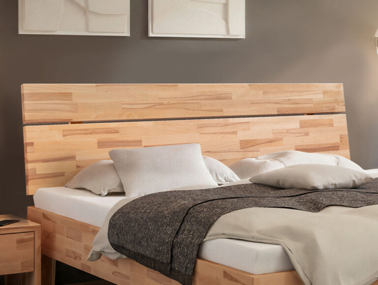 Ein Bettgestell aus hellem Holz mit einem Kopfteil aus horizontalen Latten, bestückt mit einer weißen Matratze und grauer sowie beiger Bettwäsche.