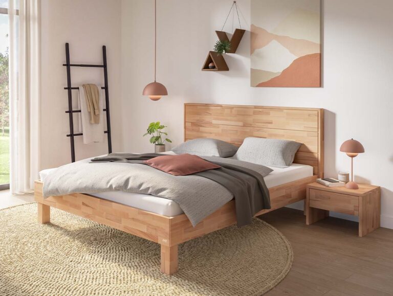 Ein Bettgestell aus hellem Holz mit passendem Nachttisch, kombiniert mit grauer Bettwäsche und einem runden Juteteppich.