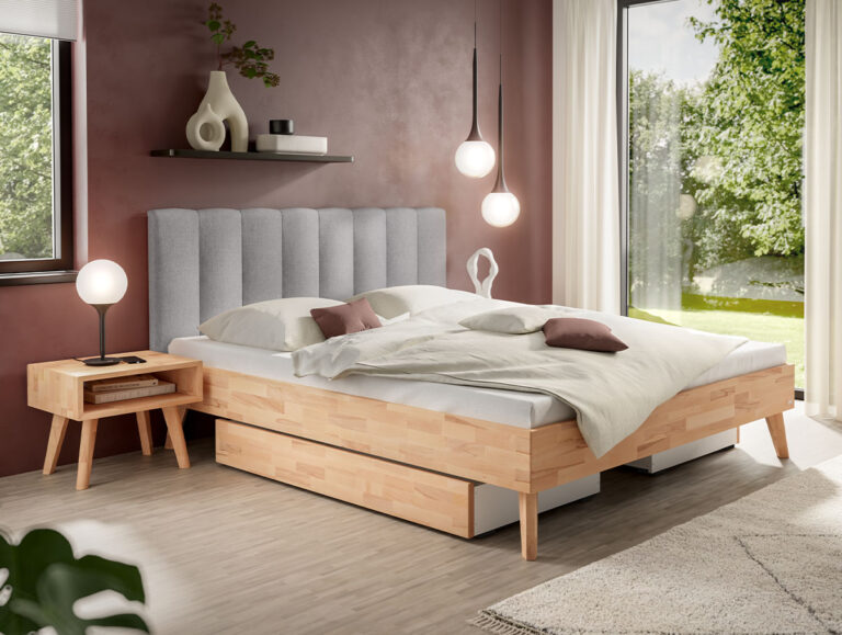 Ein Plattformbett aus Holz mit einem grauen, gepolsterten Kopfteil, Stauraumschubladen unter dem Bett und einem passenden Nachttisch aus Holz.