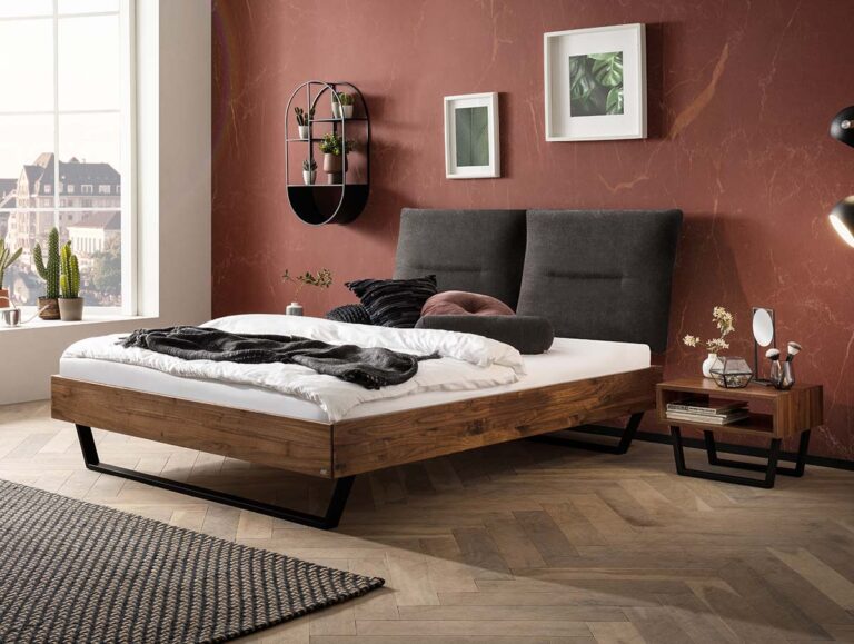 Ein Bett mit Holzrahmen und dunkelgrauem, gepolstertem Kopfteil vor einer rostfarbenen Wand, daneben ein passender Nachttisch aus Holz.