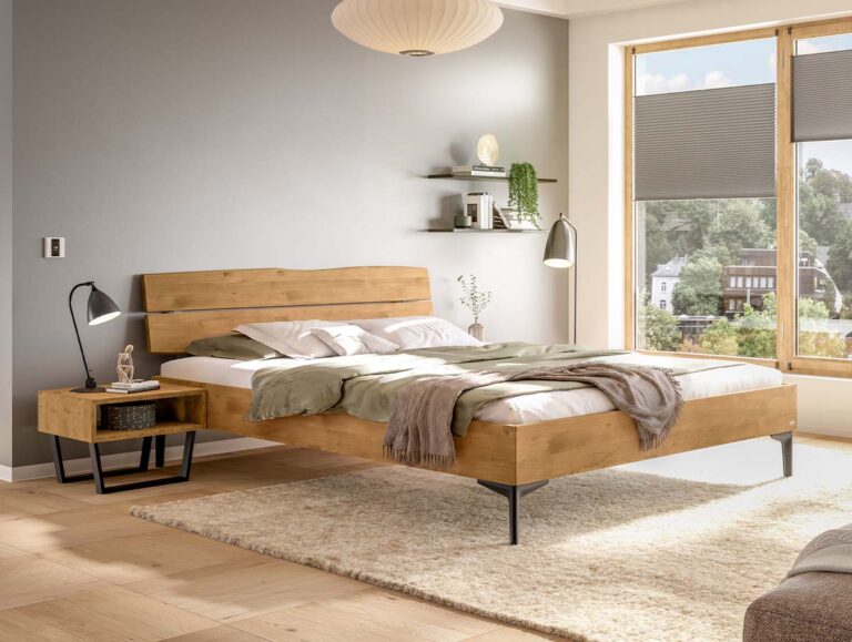 Ein Bettgestell aus Holz mit Kopfteil und schwarzen Metallbeinen, das in einem Schlafzimmer neben einem passenden Nachttisch steht.